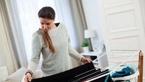 Eine Frau hängt in einer Wohnung Wäsche auf