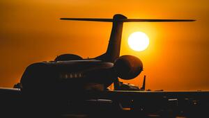 Silhouette eines Flugzeugs am Boden vor einem orangefarbenen Sonnenuntergang mit der Sonne knapp ...