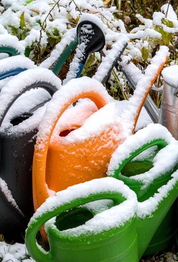 Gießkannen mit Schnee überdeckt