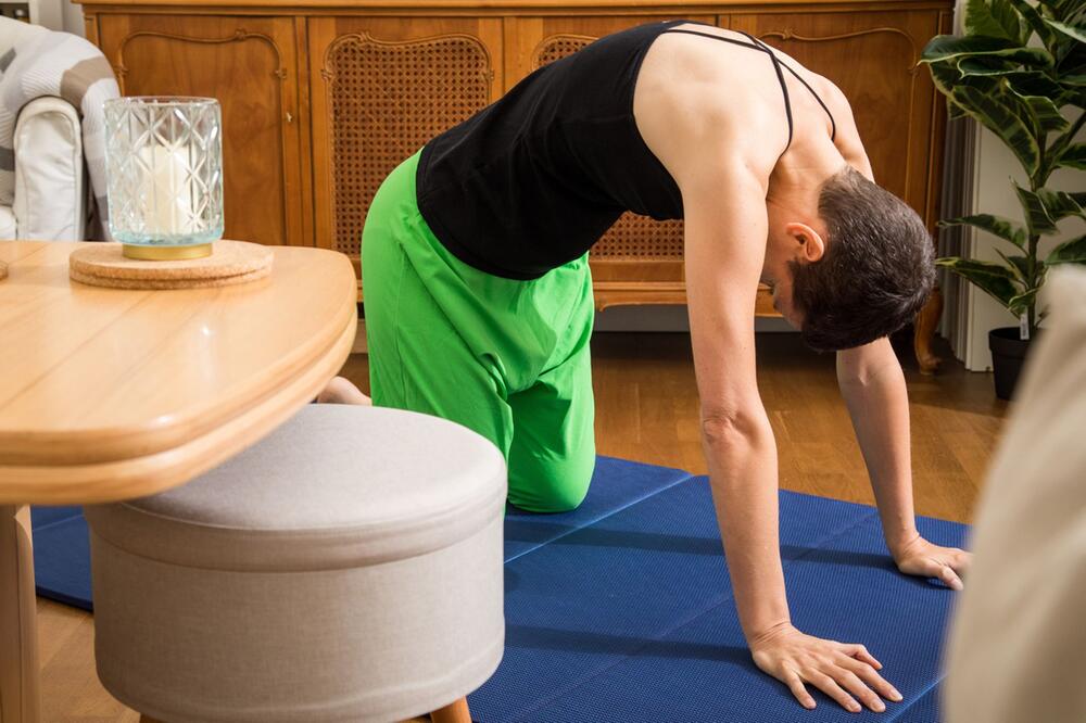 Frau macht die Yoga-Übung "Katze-Kuh"