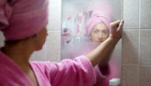 Eine Frau wischt über einen Spiegel.