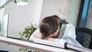 Eine Frau legt ihren Kopf erschöpft auf den Schreibtisch