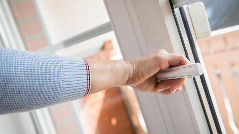 Eine Frau öffnet ein Fenster