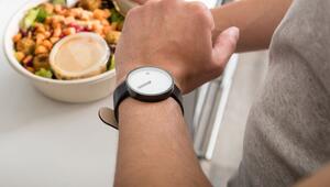 Mann mit einem Salat in der Hand schaut auf seine Armbanduhr