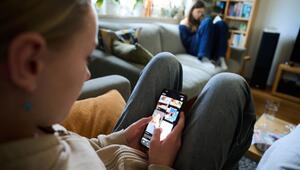 Ein Mädchen scrollt auf einem Smartphone im Wohnzimmer
