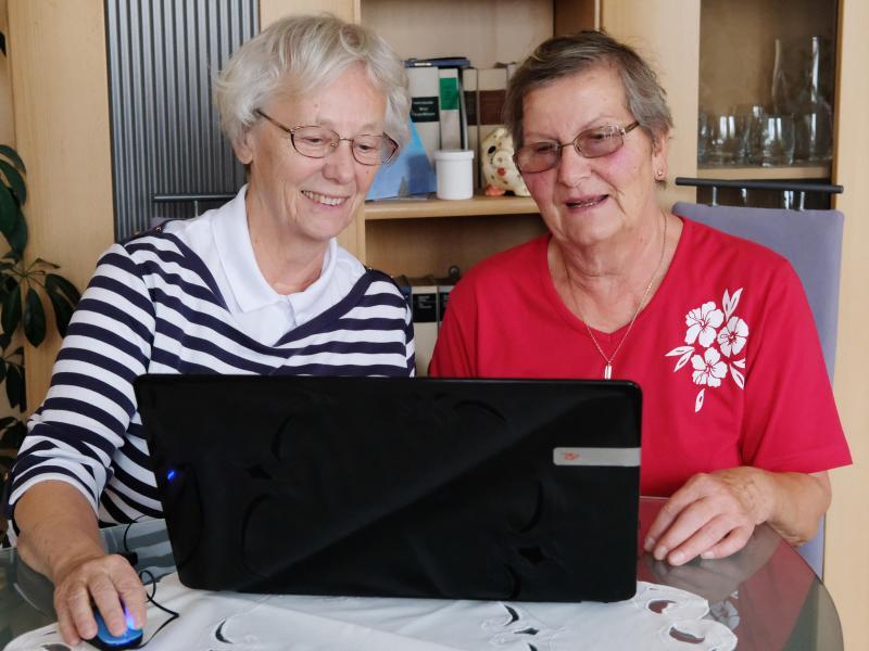 Zwei Seniorinnen sitzen vor Laptop