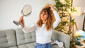 Frau mit Locken betrachtet sich im Spiegel 