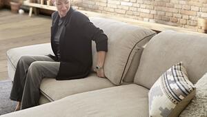 Eine Frau beim Probesitzen auf einem neuen Sofa