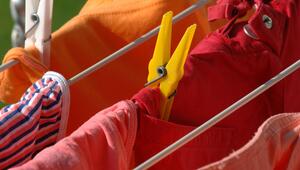 Bunte Kleidung hängt mit Wäscheklammern befestigt auf einem Wäscheständer.