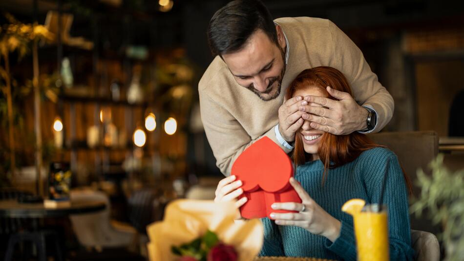 Ein Mann überrascht eine Frau mit einem Geschenk