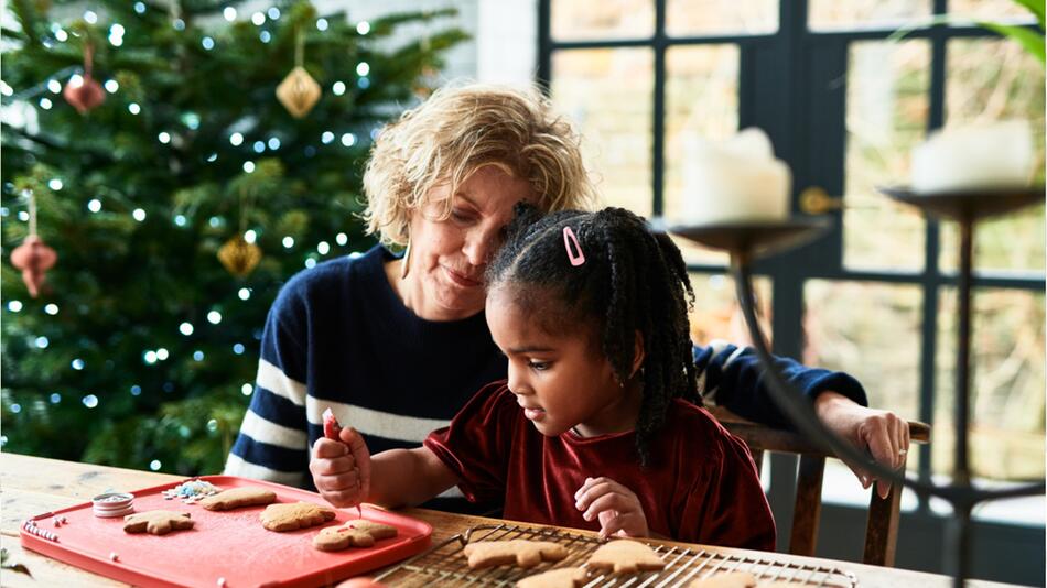 Frau und Kind backen gemeinsam Weihnachtsplätzchen.