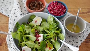 Schüsseln mit Feldsalat und Granatapfelkernen auf einem Tisch