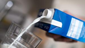 Mann gießt Milch aus einem Karton in ein Glas