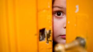 Kind schaut durch einen Türschlitz