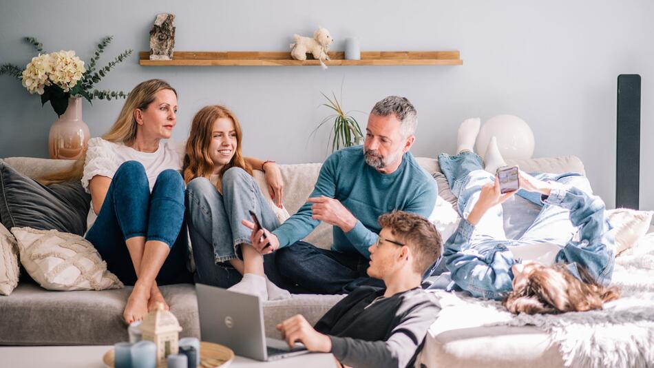 Familie unterhält sich gemeinsam in einem Wohnzimmer