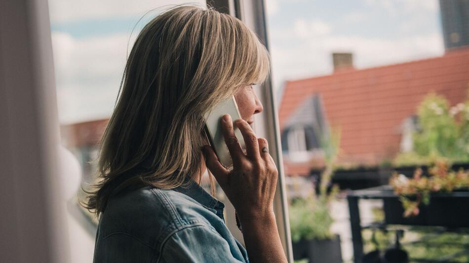 Eine Frau telefoniert am Fenster
