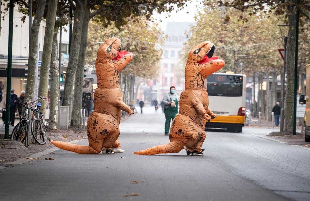 Karnevalistinnen in aufblasbaren Dinosaurier-Kostümen