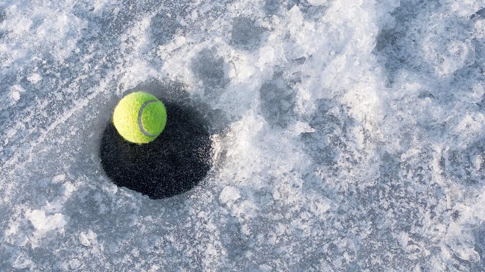 Tennisball liegt auf Eisfläche