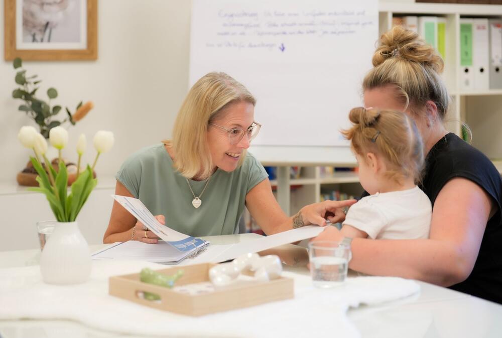 Tanja Voßen im Gespräch mit einer Mutter und ihrem Kind