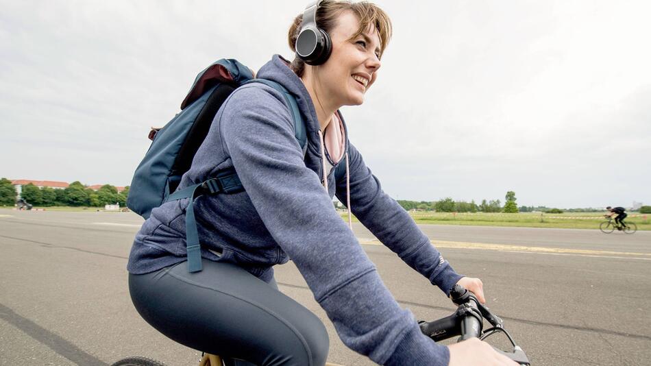 Eine Frau trägt beim Fahrradfahren einen Kopfhörer