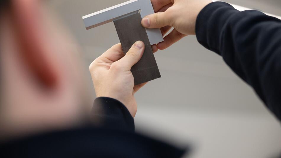 Ein Auszubildender bearbeitet ein Metallstück