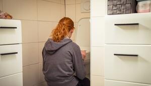 Frau hockt vor einer Toilette im Badezimmer