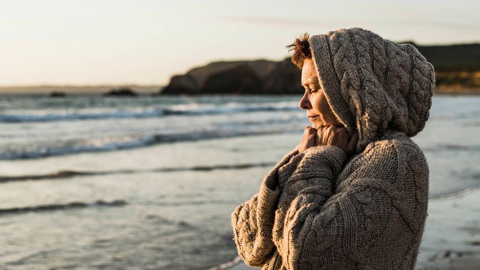 Eine Frau steht bei Sonnenuntergang am Strand