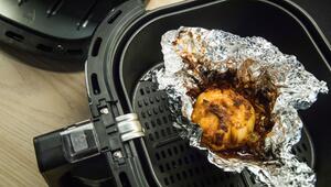 Eine in Alufolie gewickelte Zwiebel liegt in einem Airfryer