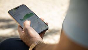 Ein Mann hält ein Smartphone mit einer Finanz-App in der Hand