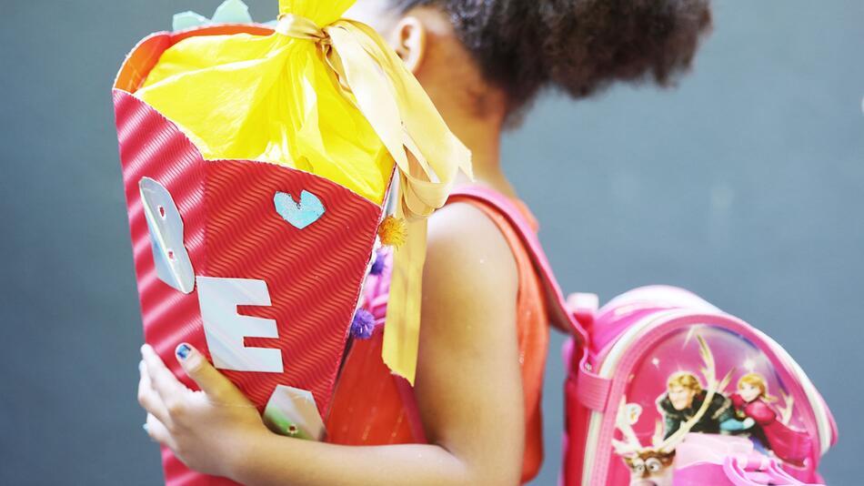Ein Kind hält bei der Einschulung eine Schultüte im Arm