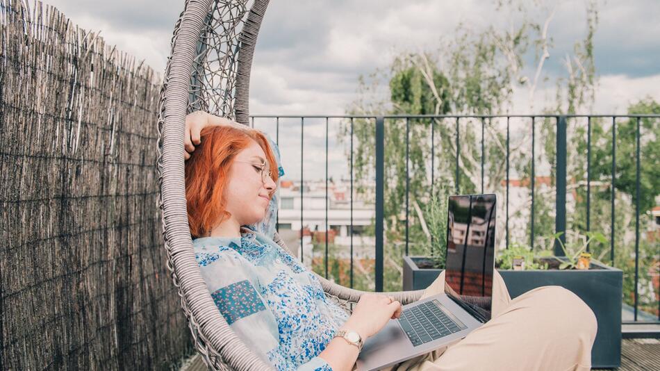Eine Frau arbeitet auf einer Terrasse im Homeoffice
