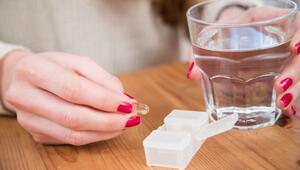 Eine Frau hält eine Kapsel und ein Glas Wasser in der Hand