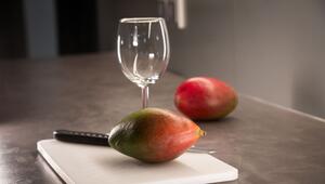 Mango liegt neben einem Weinglas auf einem Schneidebrett