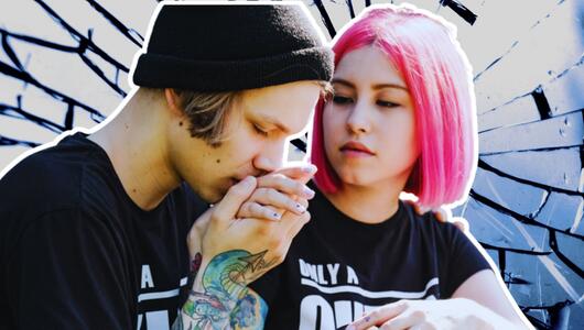 Junges Paar, er küsst ihre Hand. Sie hat pinke Haare. 