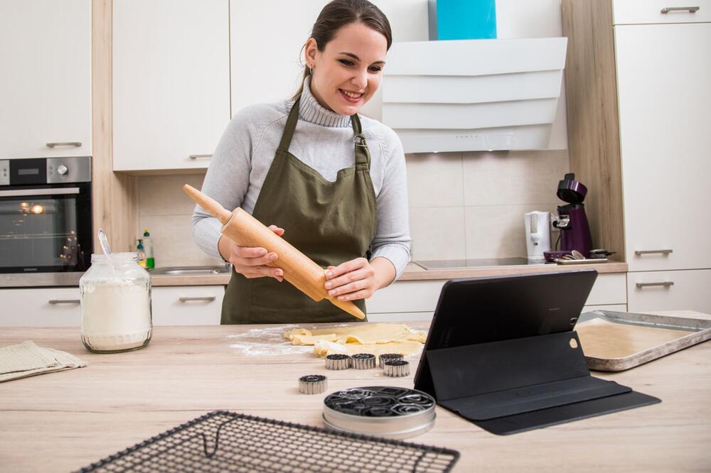 Eine Frau rollt Plätzchenteig in einer Küche aus