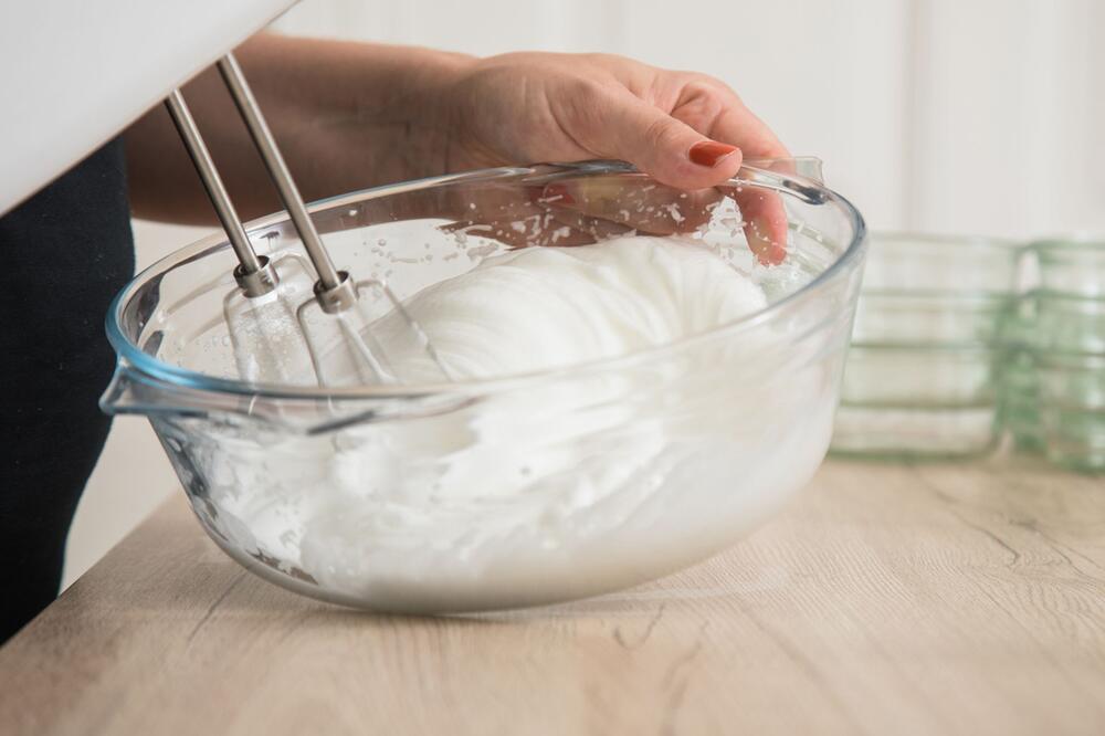 Eine Frau schlägt Eischnee in einer Schüssel auf