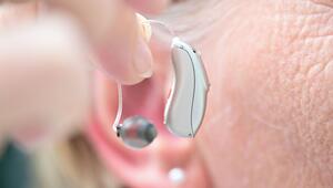 Eine Frau hält ein Hörgerät vor ihr Ohr