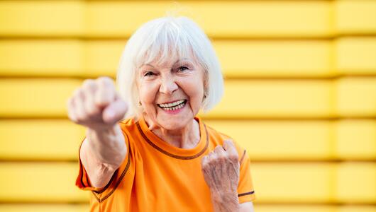 Seniorin, die gut gelaunt und sportlich aktiv ihre Faust nach vorne streckt