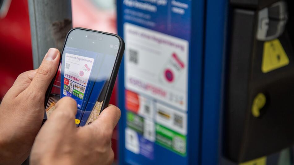 Ein Mann scannt den QR-Code einer Park-App mit einem Smartphone