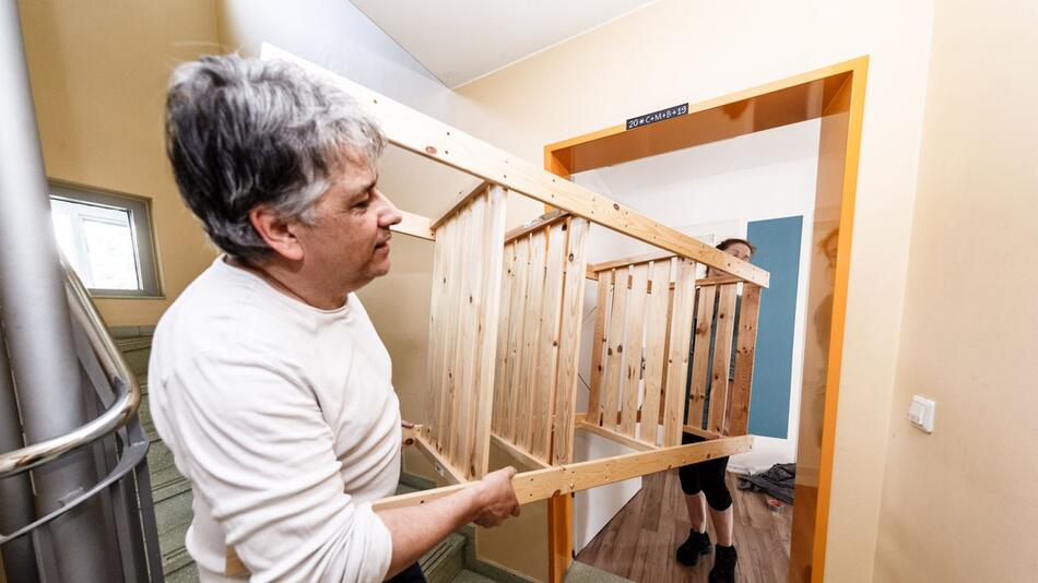 Mann trägt ein Regal durch ein Treppenhaus