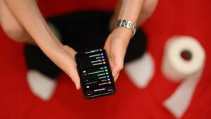 Ein junger Mann sitzt mit einem Handy auf einer Toilette