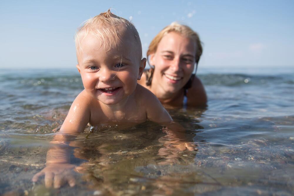 Kind und Frau baden im Meer