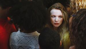Eine blonde Frau steht isoliert in einer Gruppe Menschen