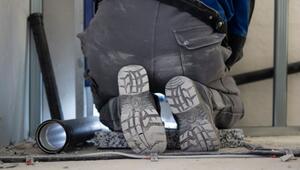 Ein Handwerker arbeitet kniend an der Sanitärinstallation