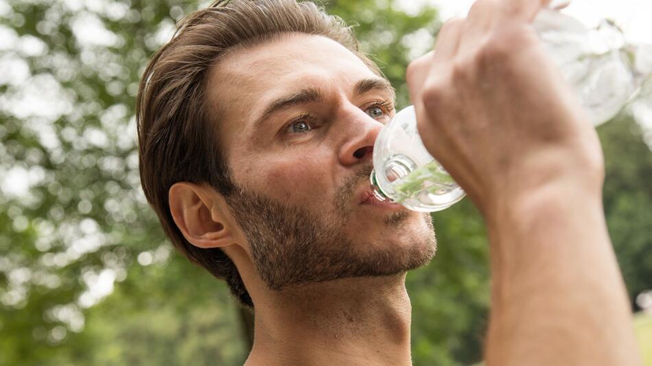 Mann trinkt Wasser aus einer PET-Flasche