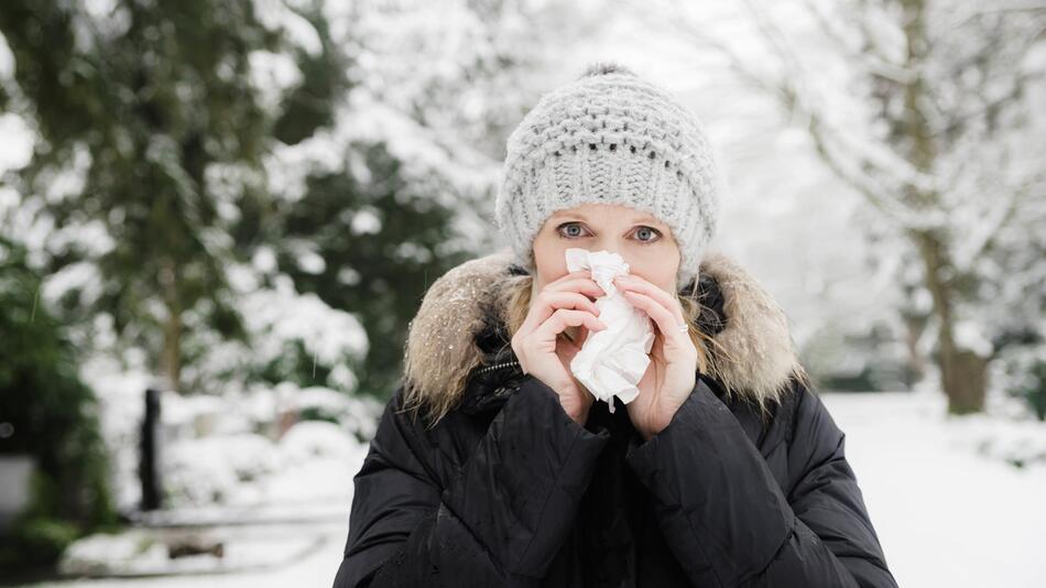 Frau im Schnee putzt sich die Nase