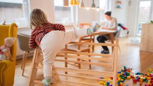 Ein zweijähriges Kind klettert im Wohnzimmer auf ein Spielgerät