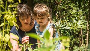 Eine Frau zeigt einem Mädchen Pflanzen im Garten