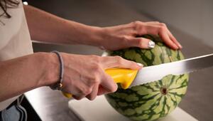 Frau schneidet eine Wassermelone auf