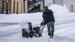 Ein Mann beräumt den Gehweg mit einer Schneefräse